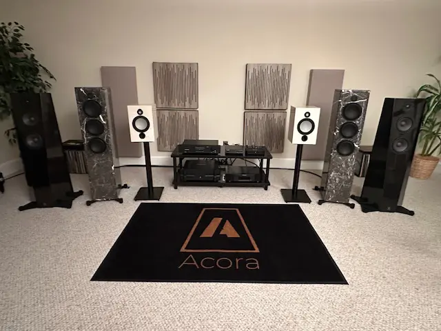 High-end audio setup with speakers, amplifier, and Accora branded rug.