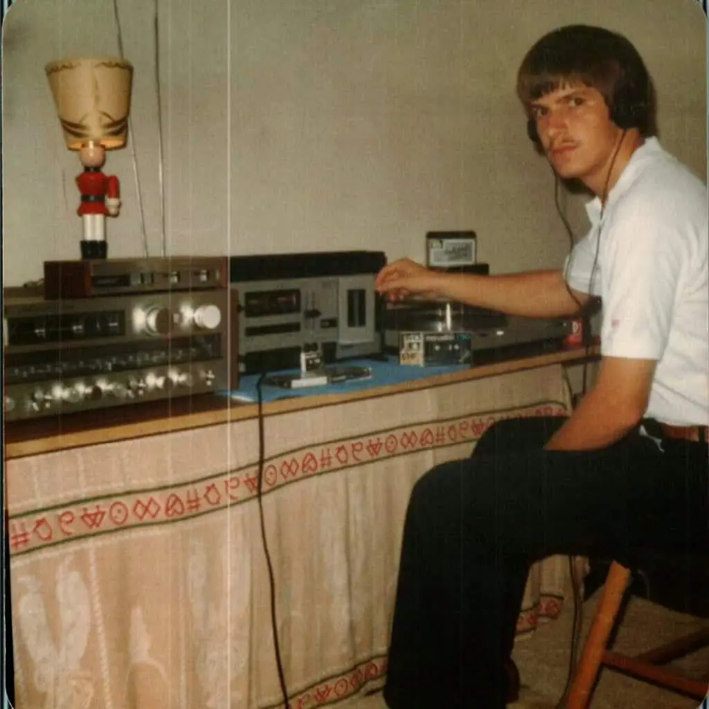Young man operating vintage radio equipment at a table.