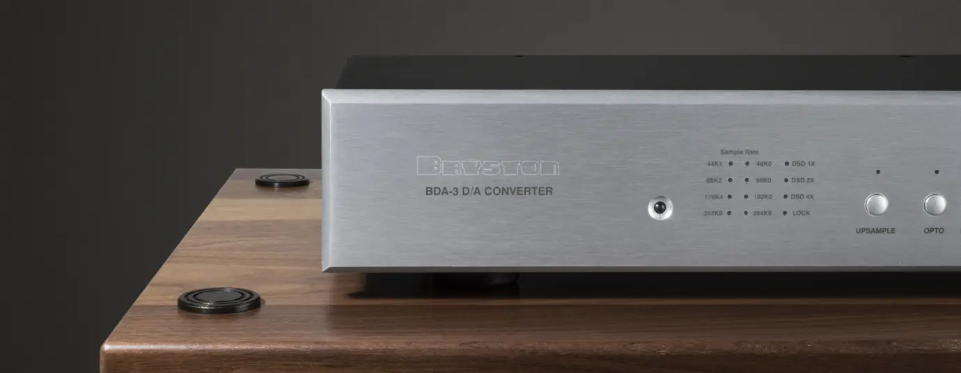 Close-up of a metal audio component with engraved text on a wooden surface.