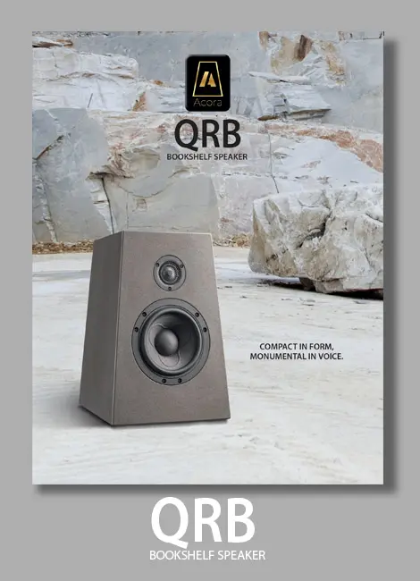 Modern wooden speaker placed on stone surface outdoors.