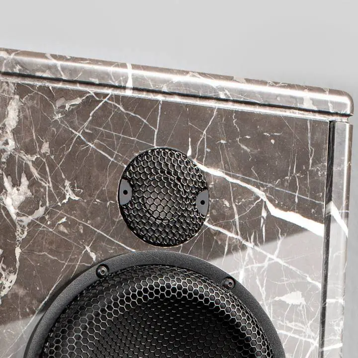 Close-up of a black speaker on a marble surface.