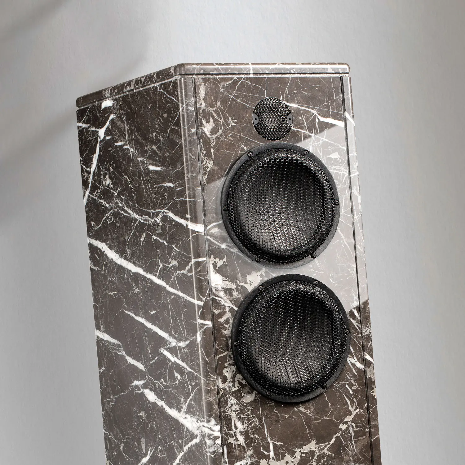 Tall speaker with a sleek black marble finish and two black speaker cones.