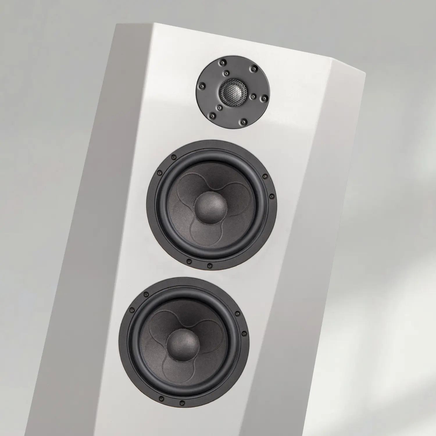 White floor-standing speaker with three drivers against a plain background.