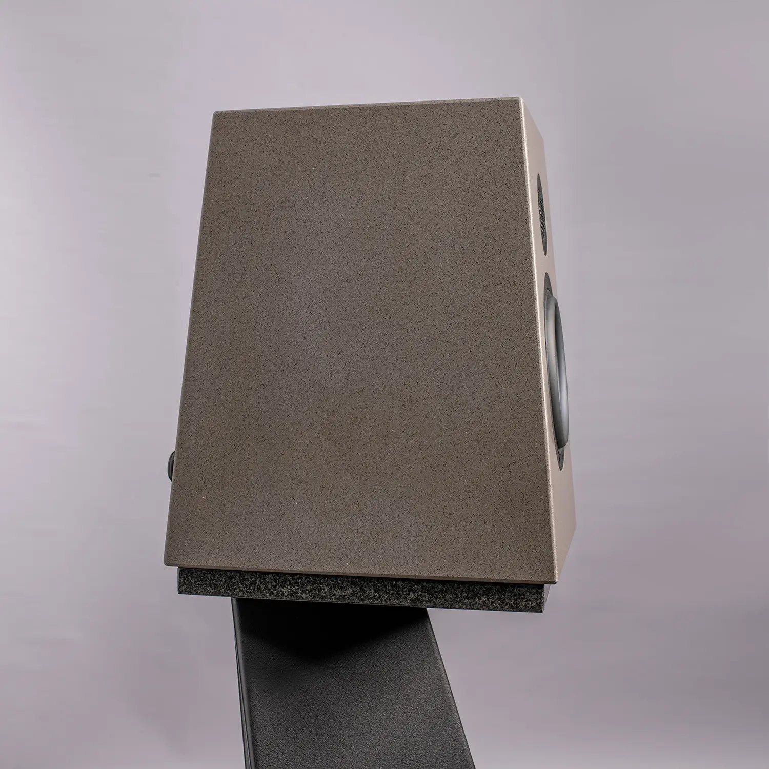 A rectangular, brown, box-like object on a stand against a plain background.