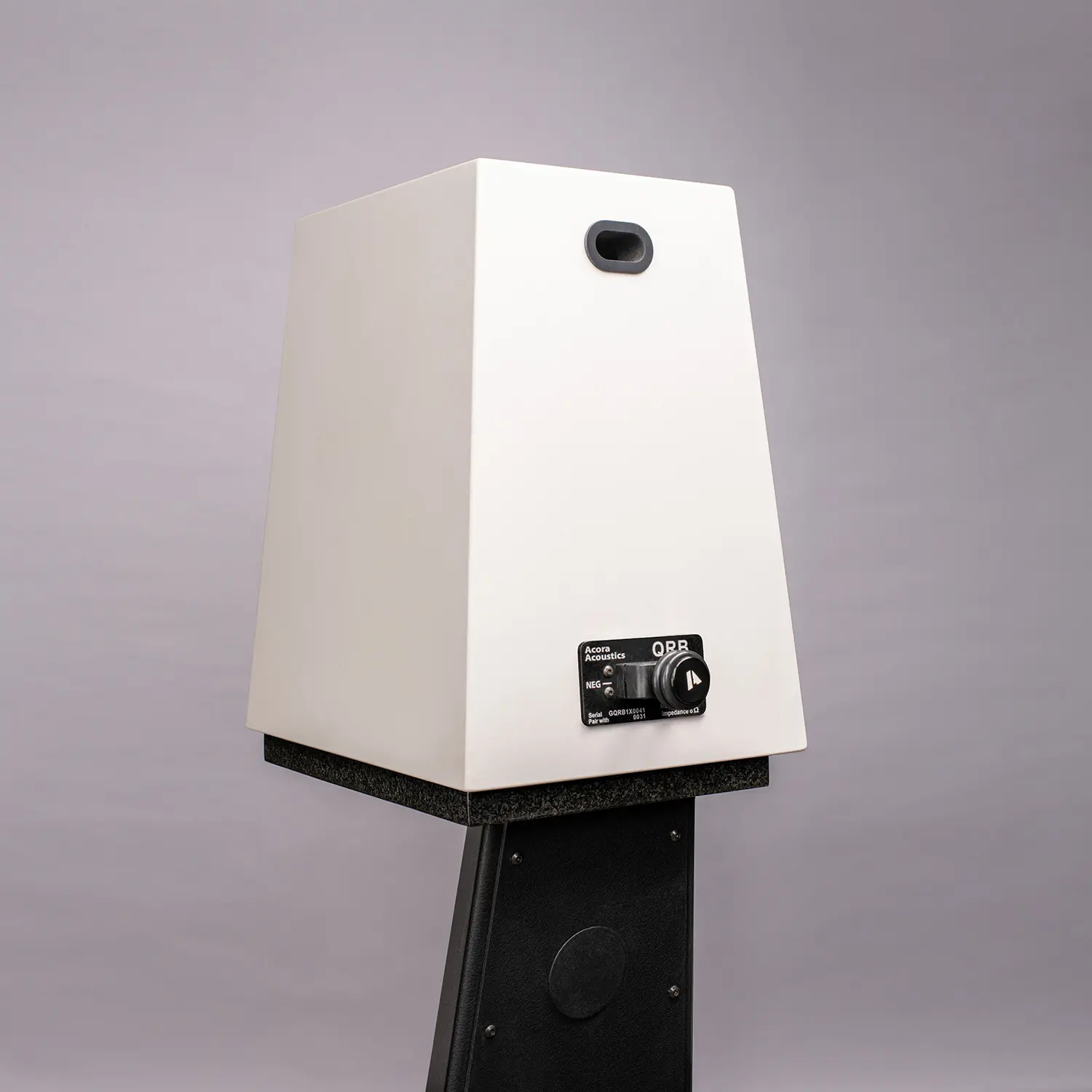 A sleek white speaker on a black stand against a light gray background.