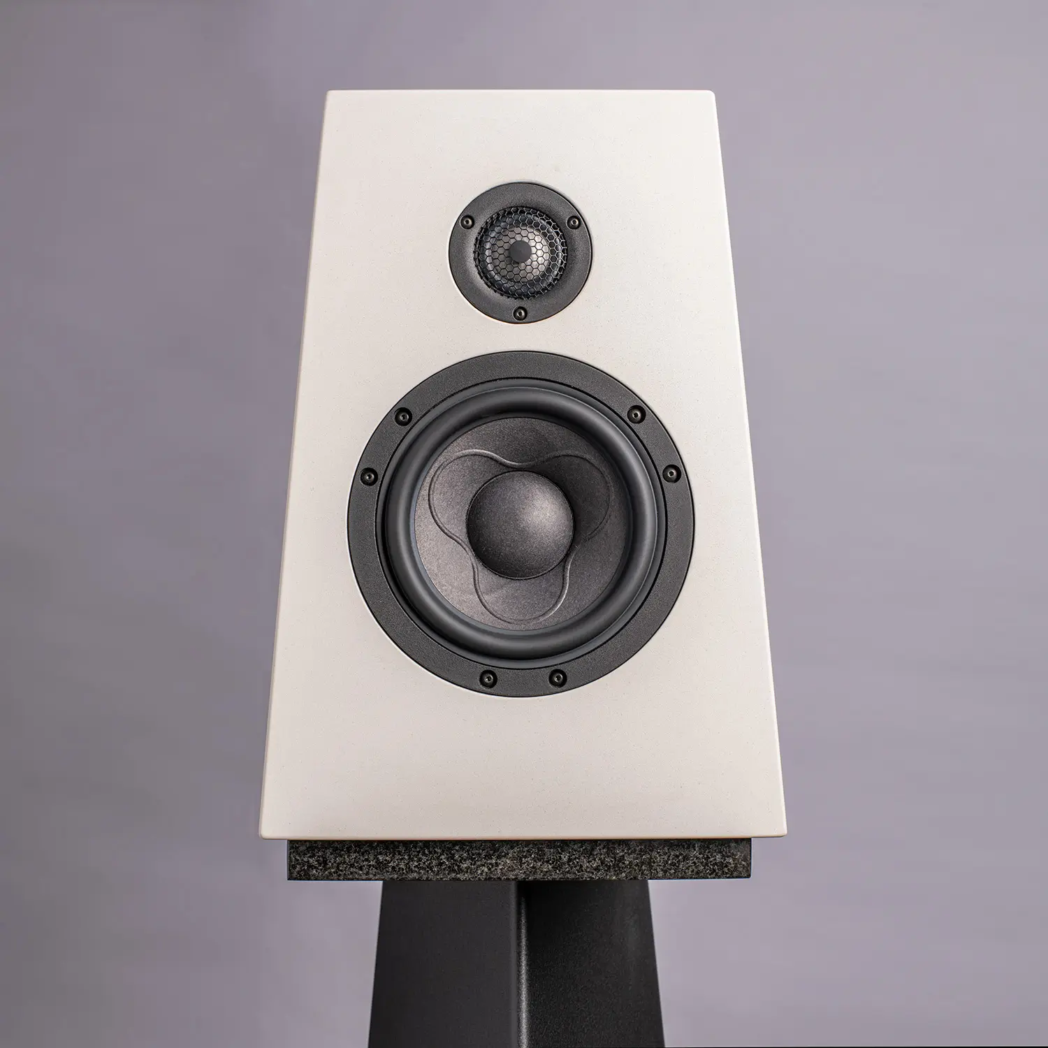 Modern white bookshelf speaker with black drivers on a stand.
