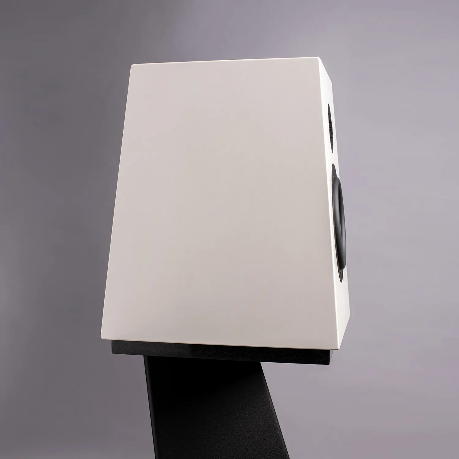 Minimalist white speaker on a black stand against gray background.