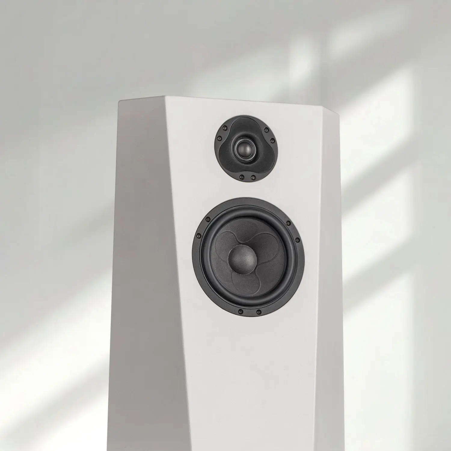 Minimalist white speaker with two drivers in natural light.