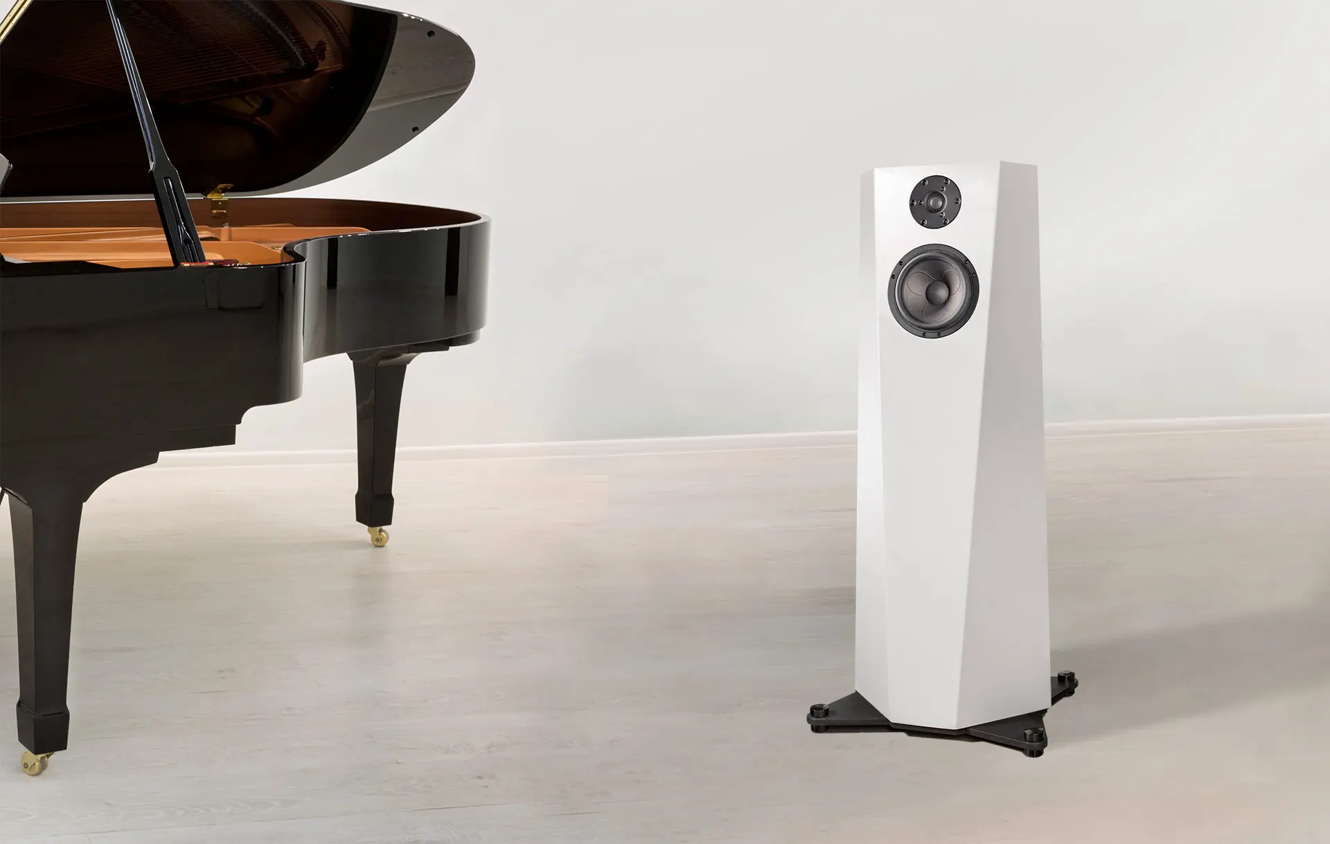 Modern white speaker and grand piano leg on a light floor.