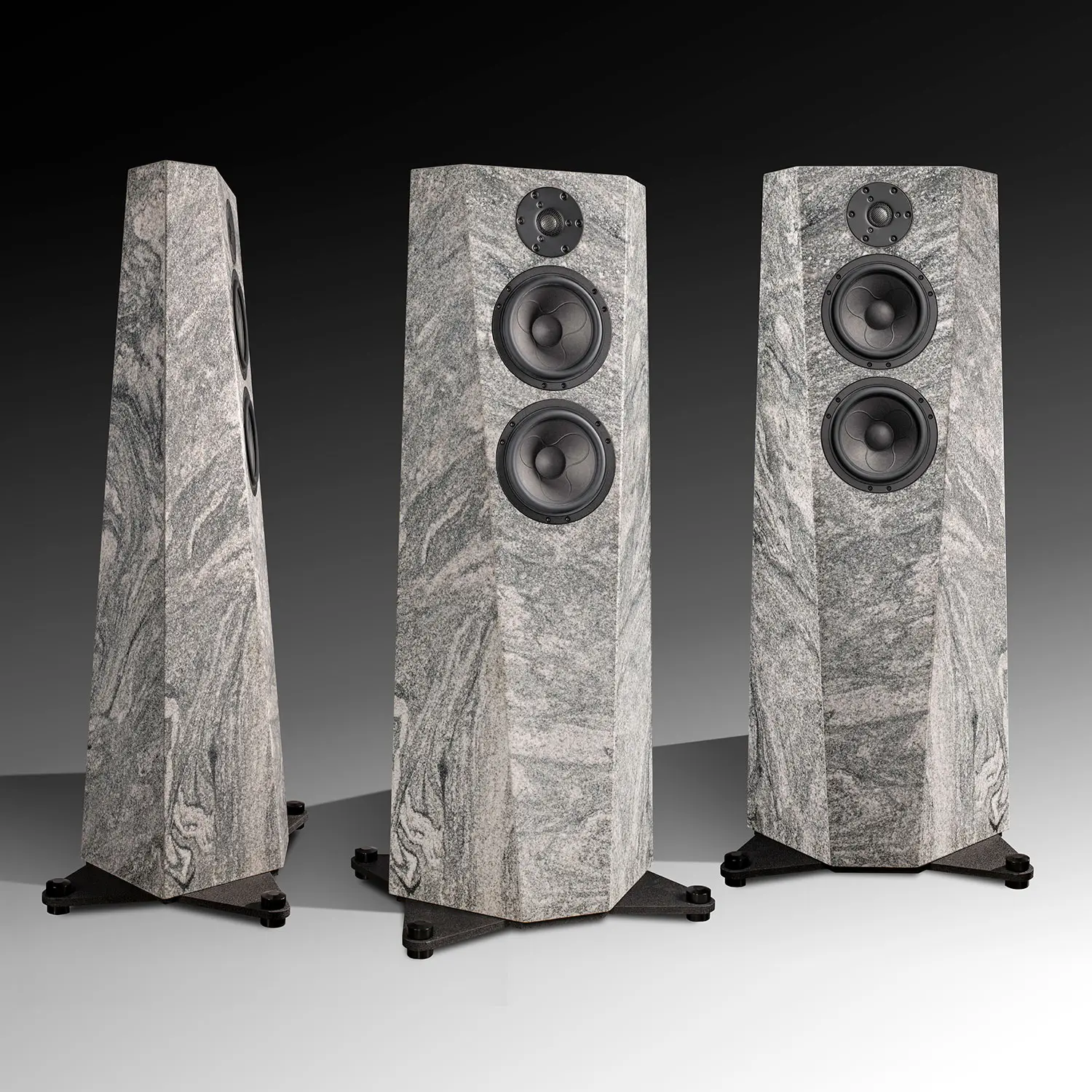 Three tall, marble-textured speakers with black speaker cones on a gray background.