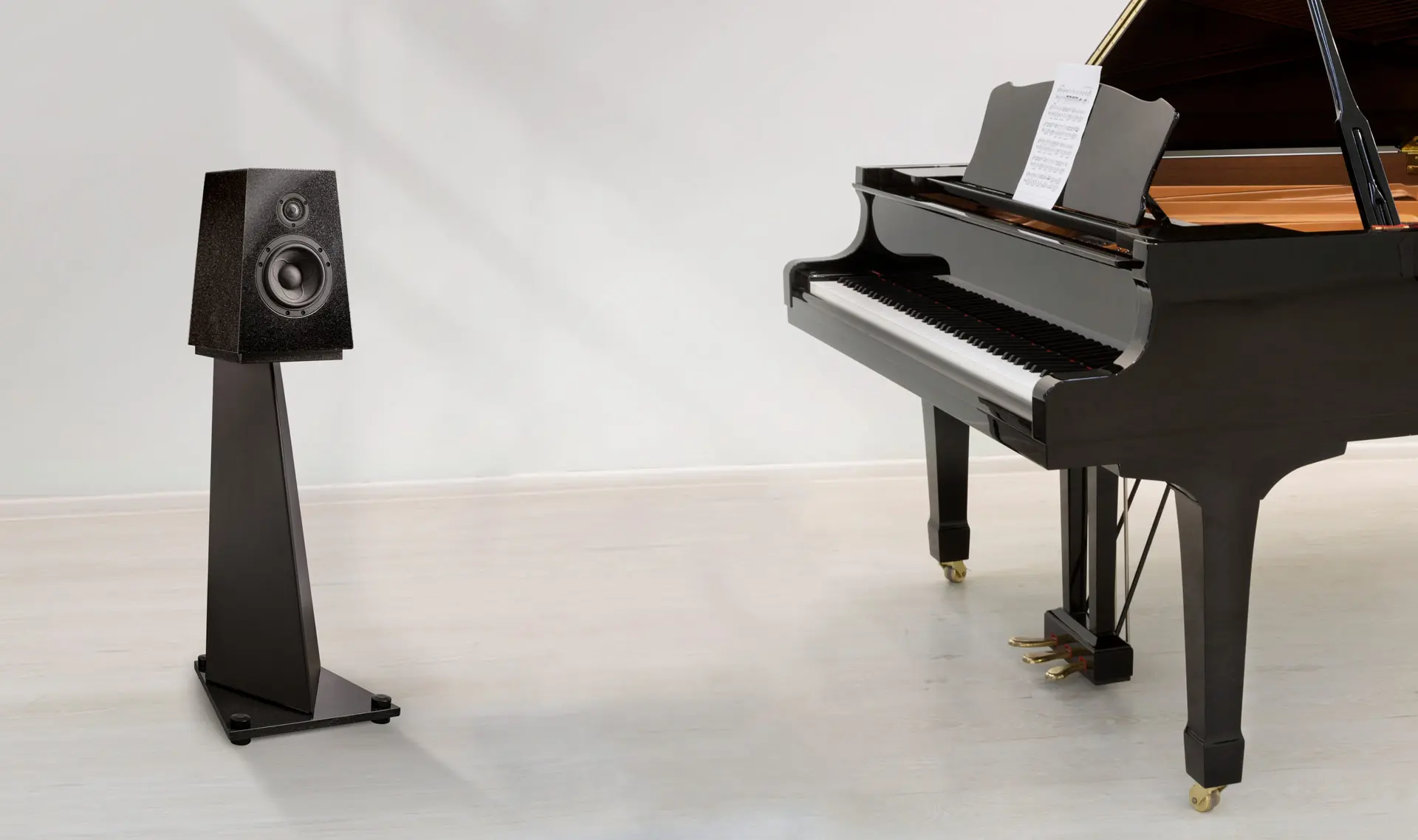 A grand piano and a speaker in a minimalist room.