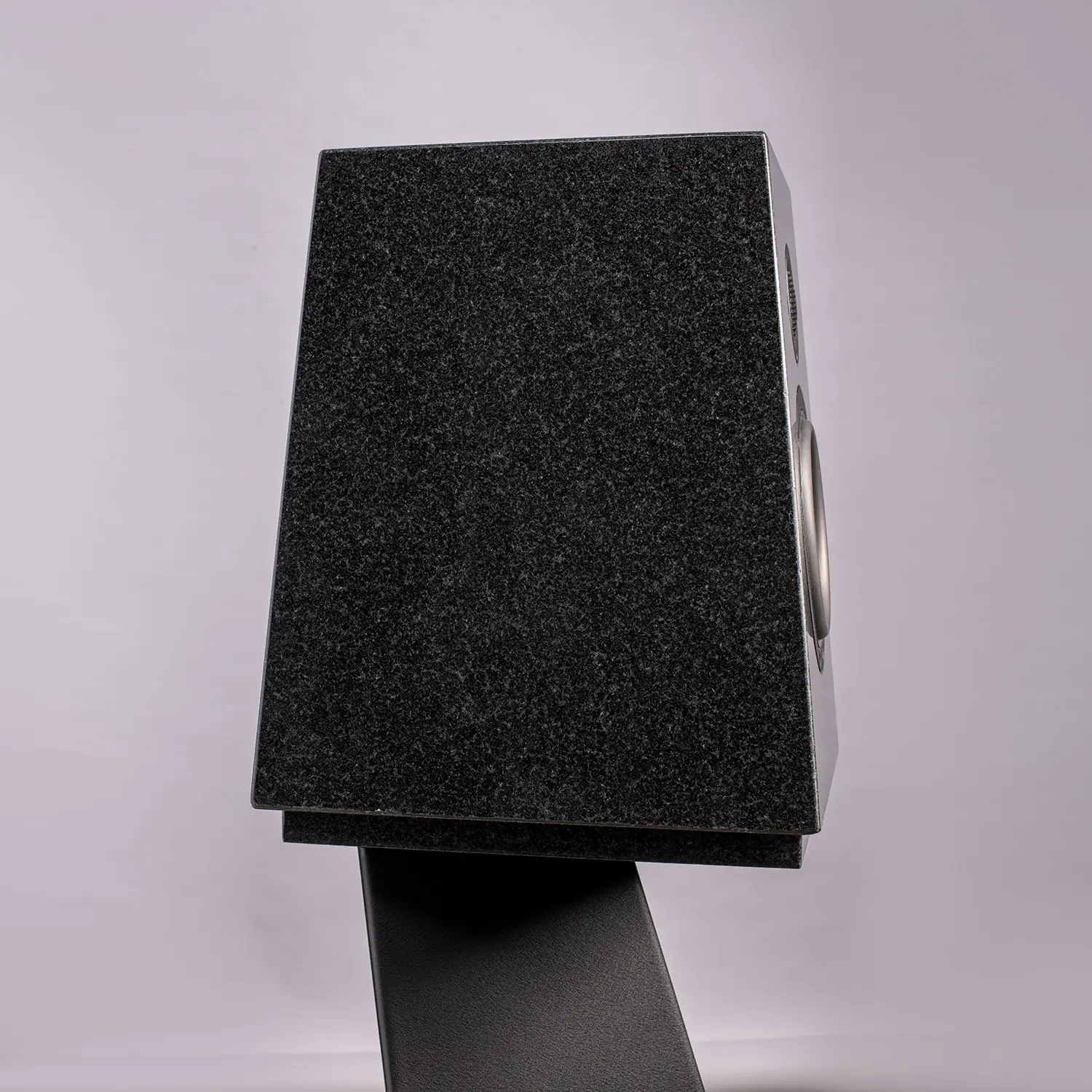 Close-up of a black speaker on a stand against a plain background.