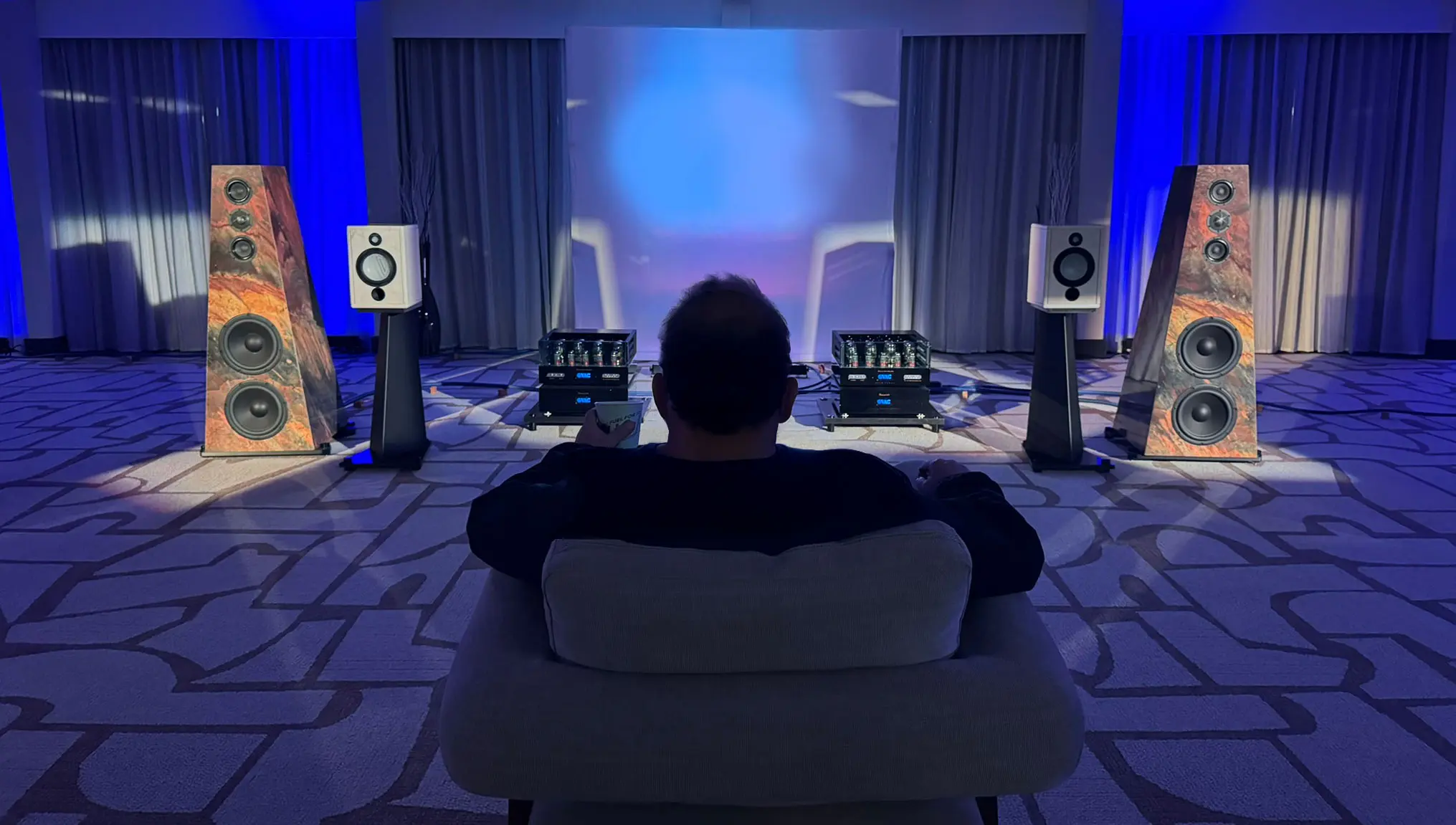 Person enjoying immersive sound experience with speakers and audio equipment.