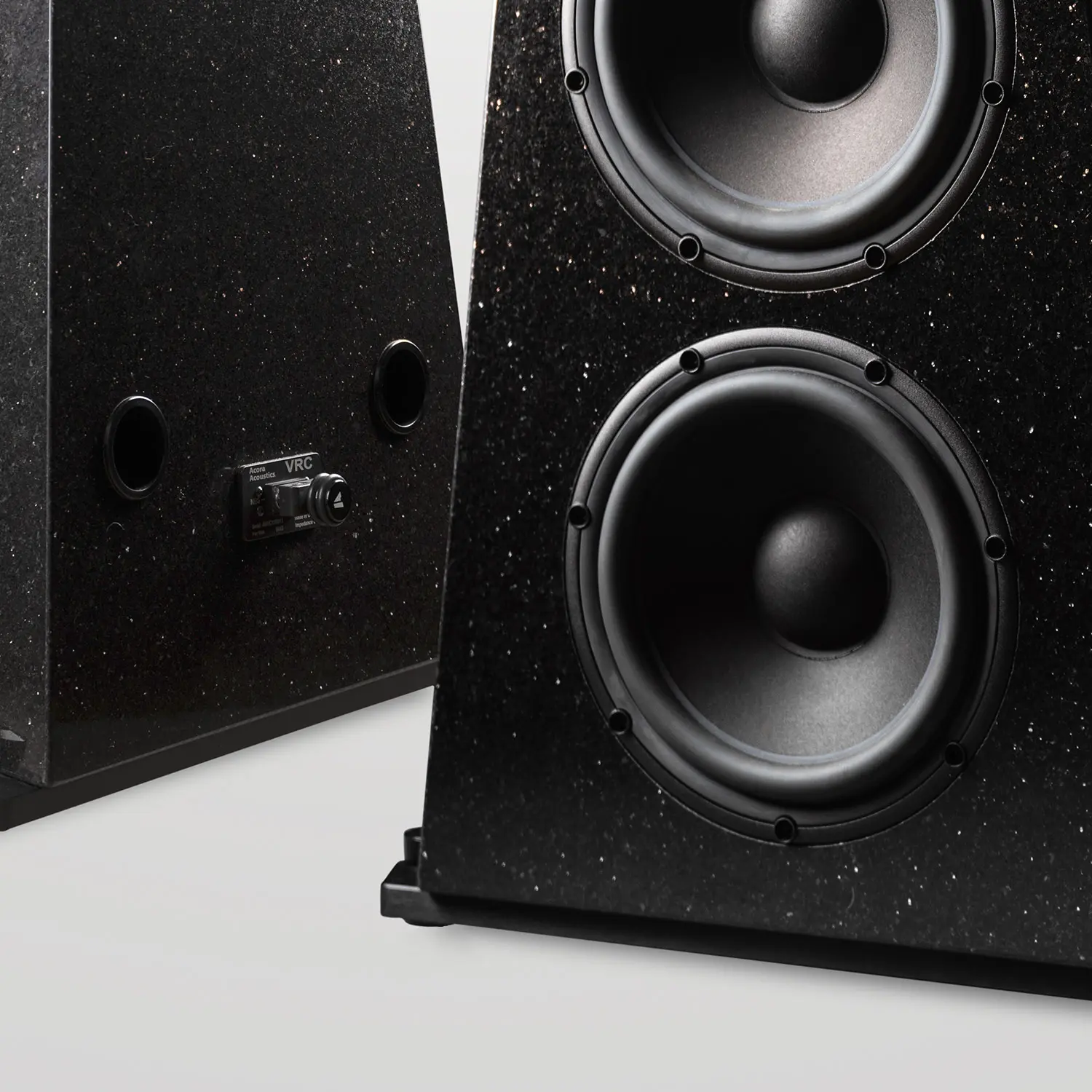 Close-up of black studio monitor speakers with textured finish.