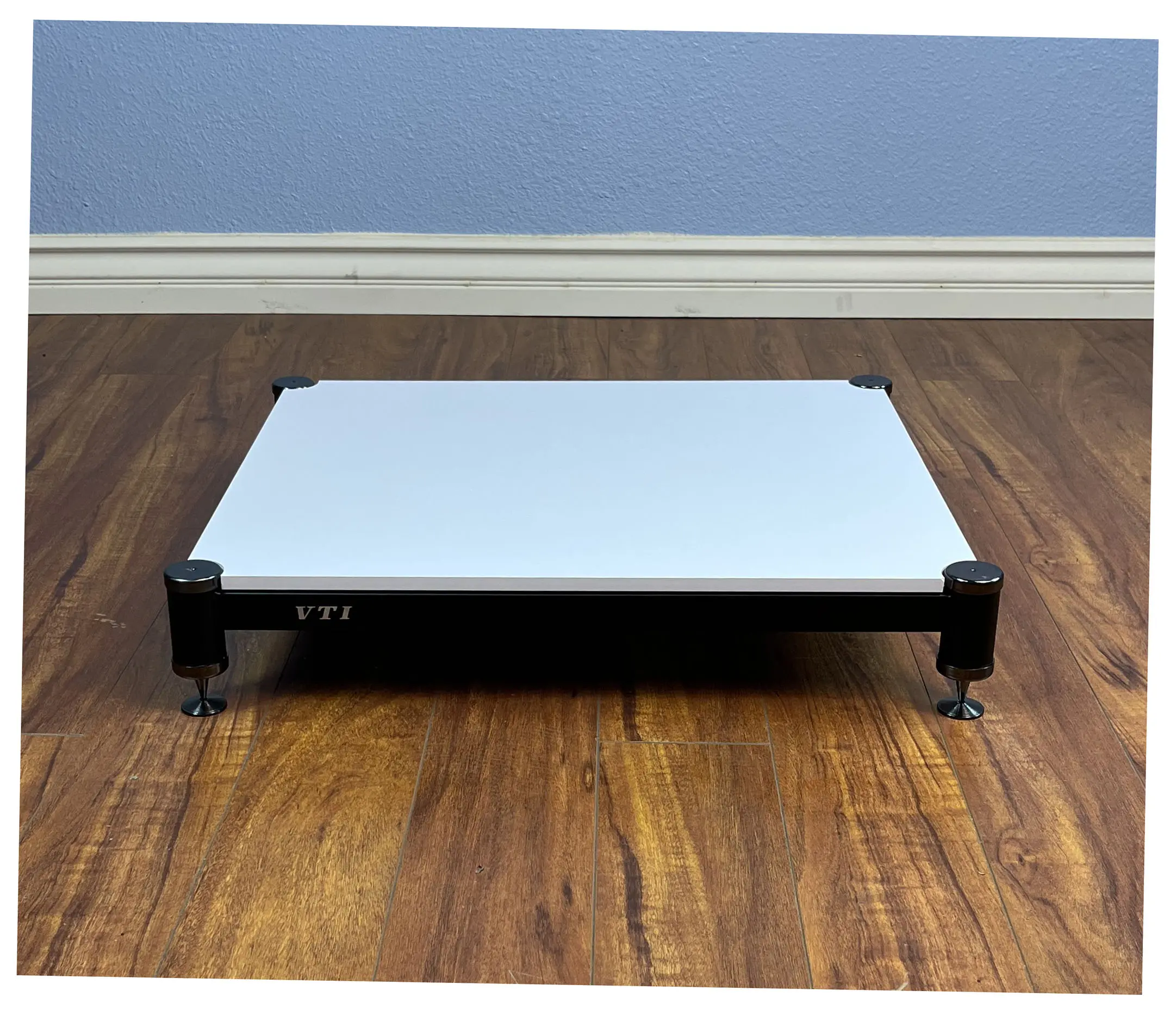 A minimalist white platform bed frame on wooden floor.