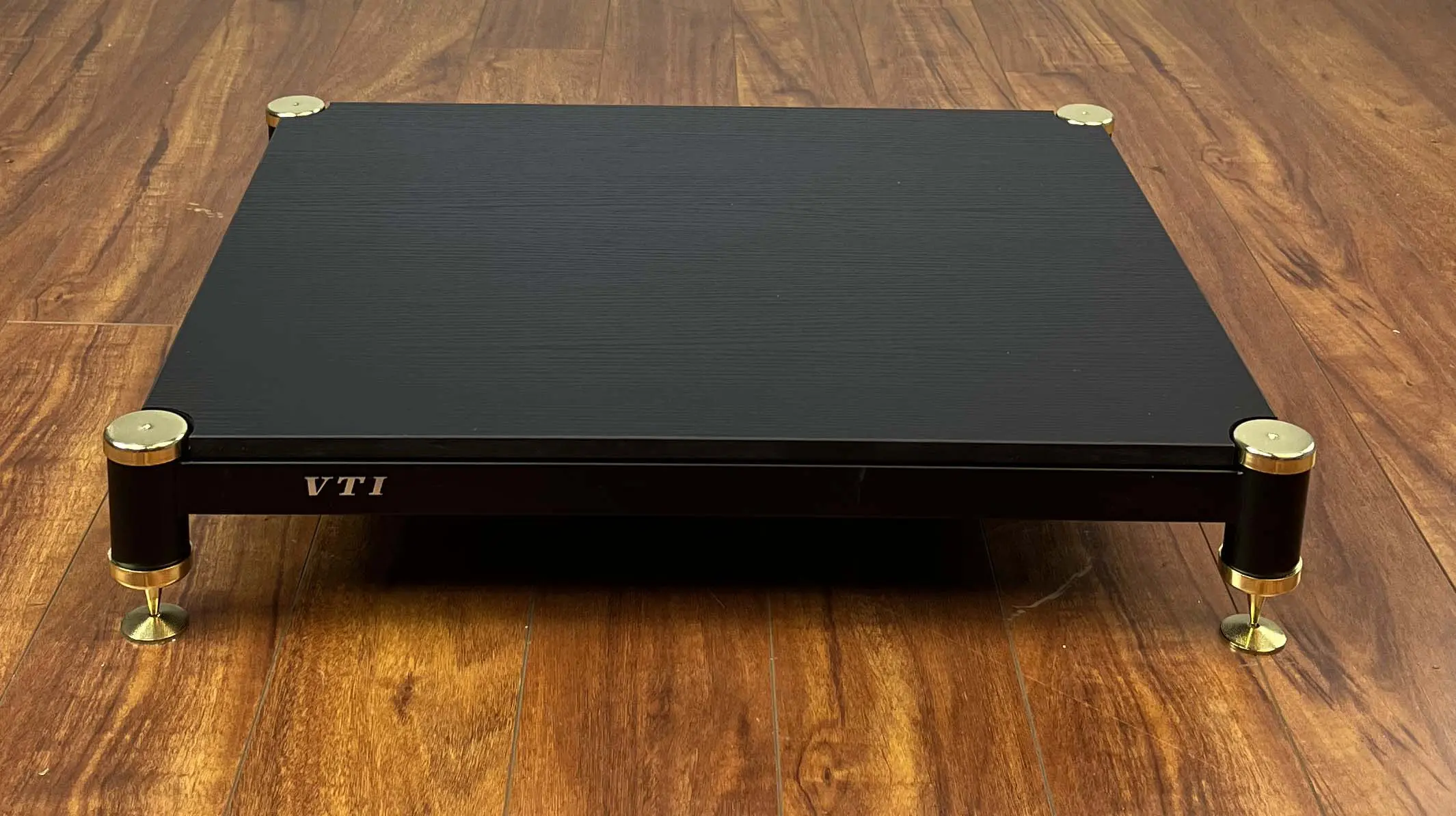 Closed black DVD player on a wooden floor.