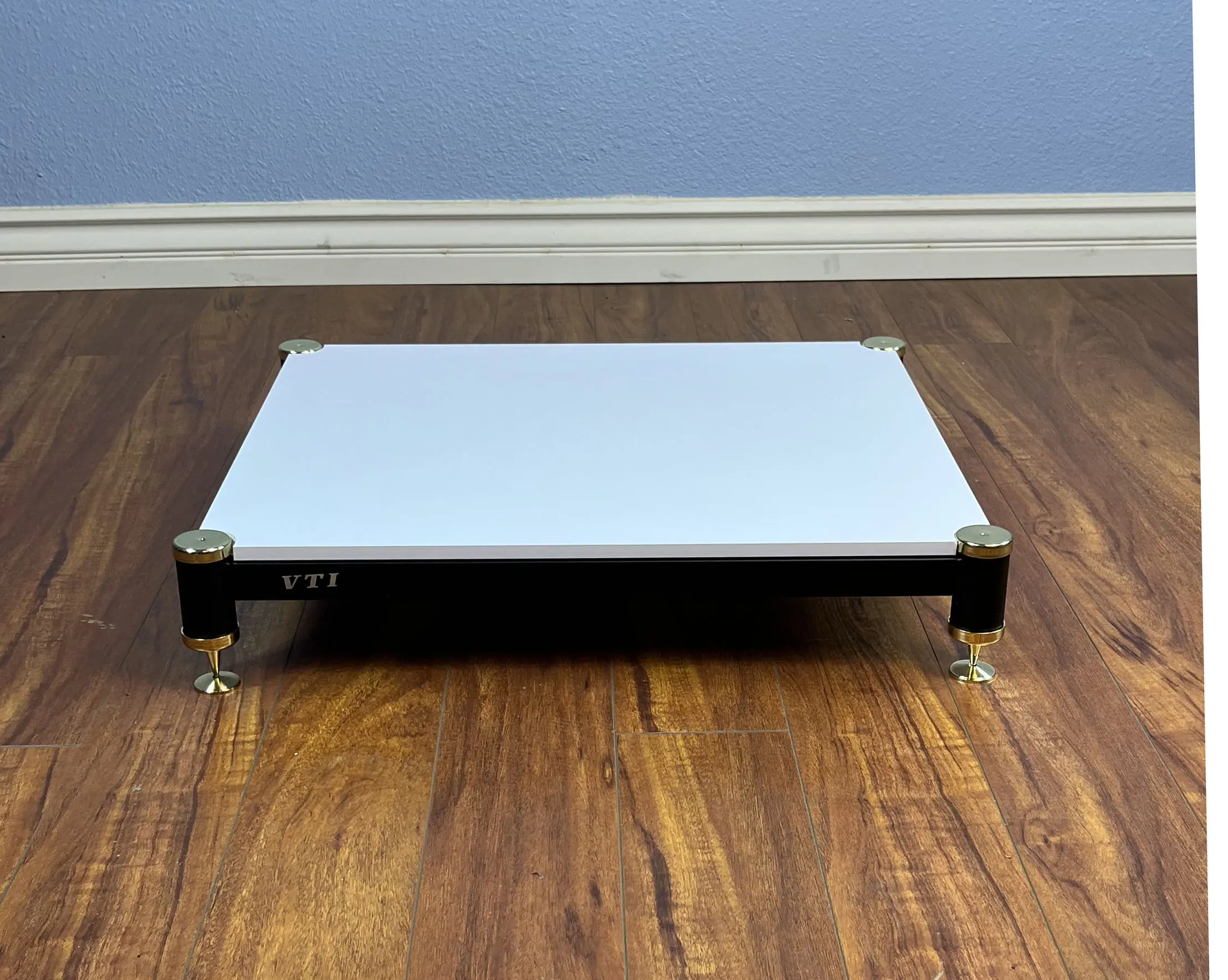 White electronic device on wooden floor with LED display.