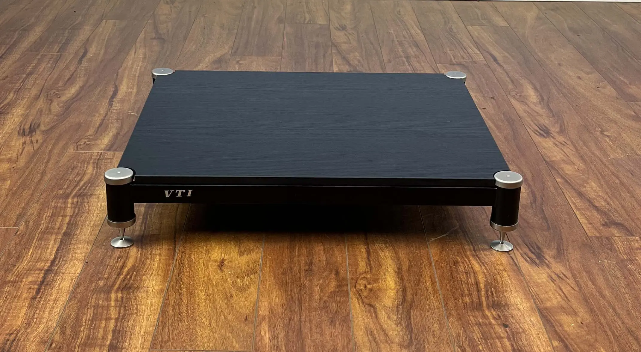 A black VTI electronic device on a wooden floor.