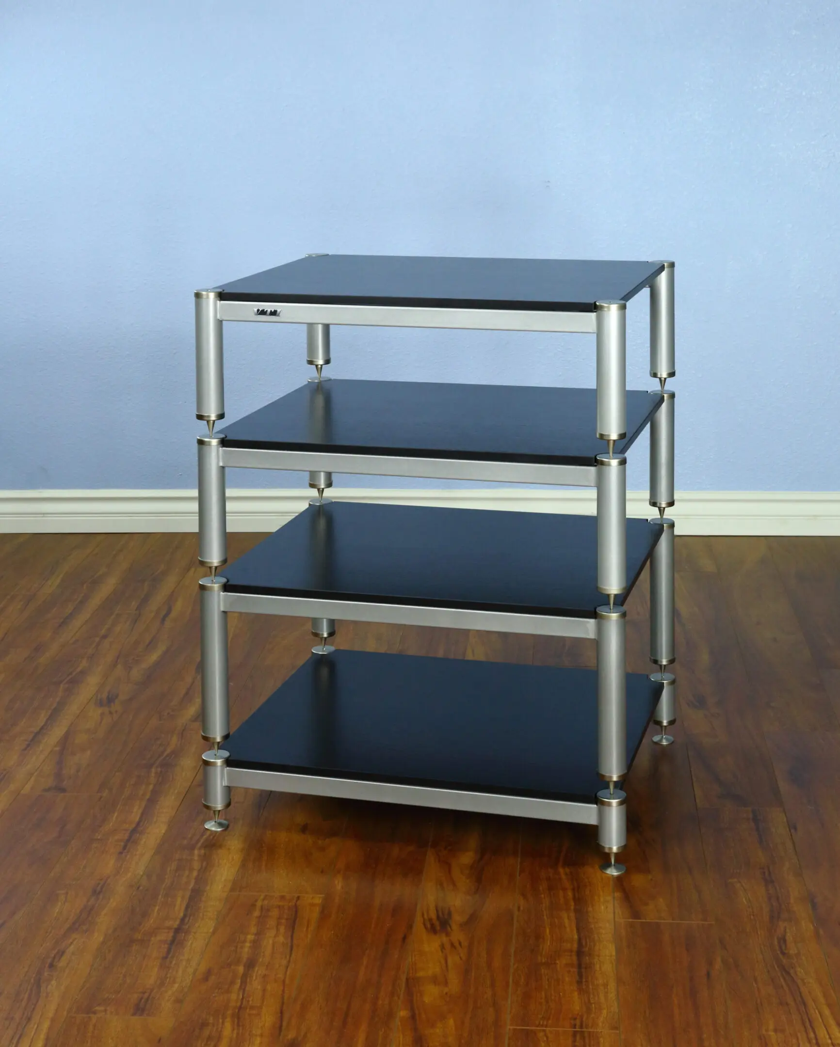 A four-tier black and silver metal shelving unit on a wooden floor.