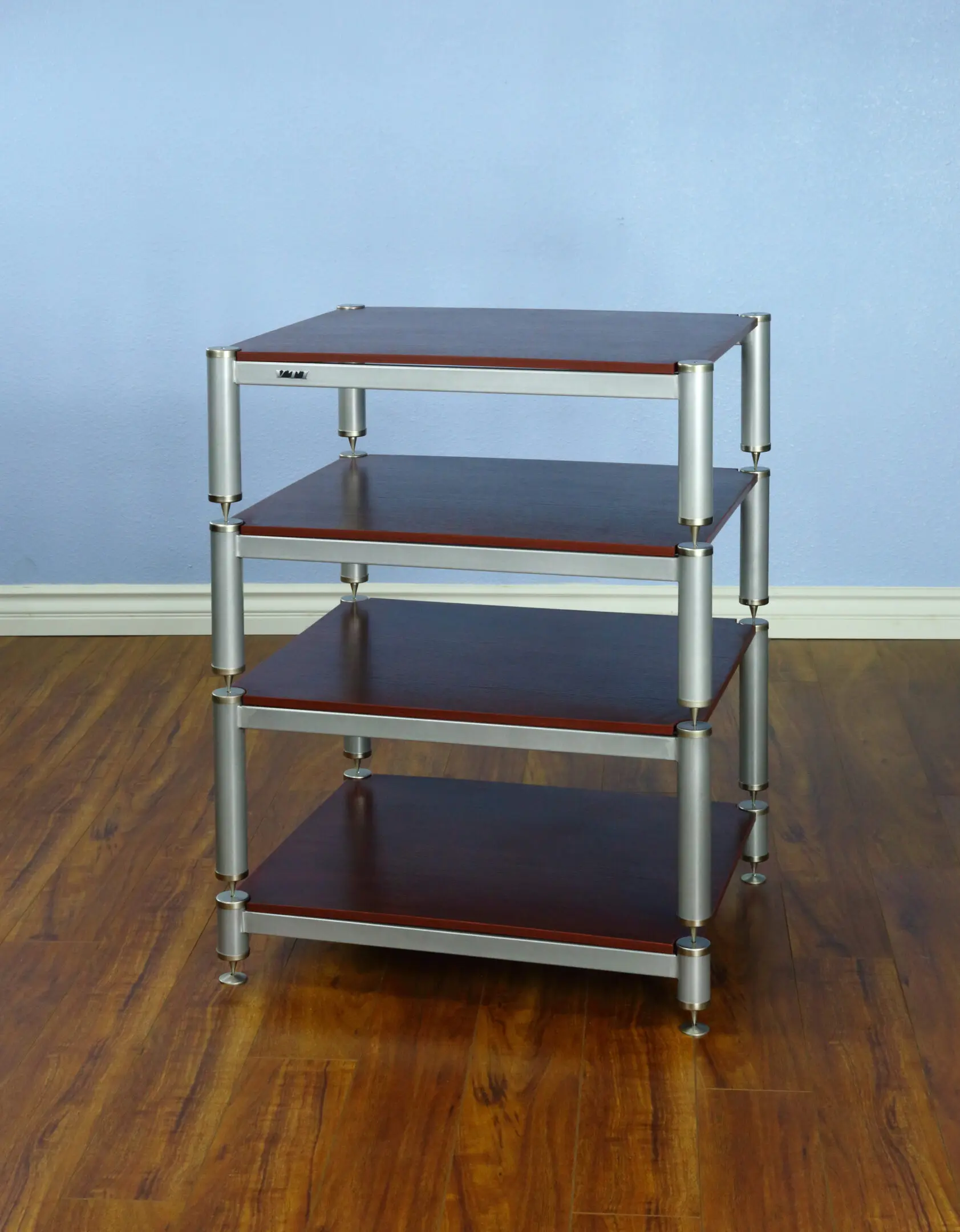 A four-tier metal and wood storage shelf on a wooden floor.