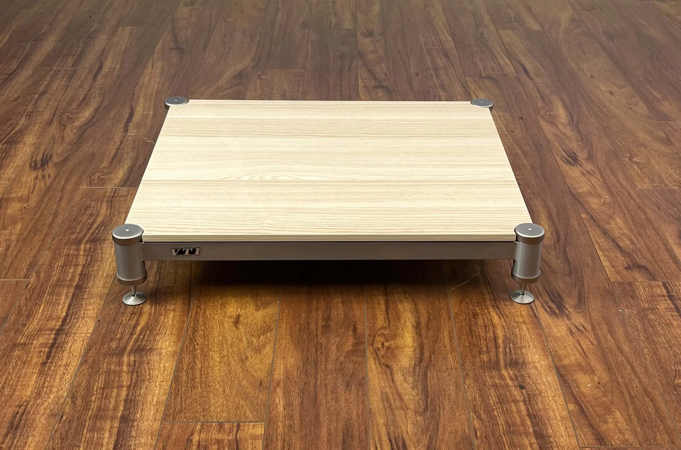 A wooden platform with metal legs on a wooden floor.