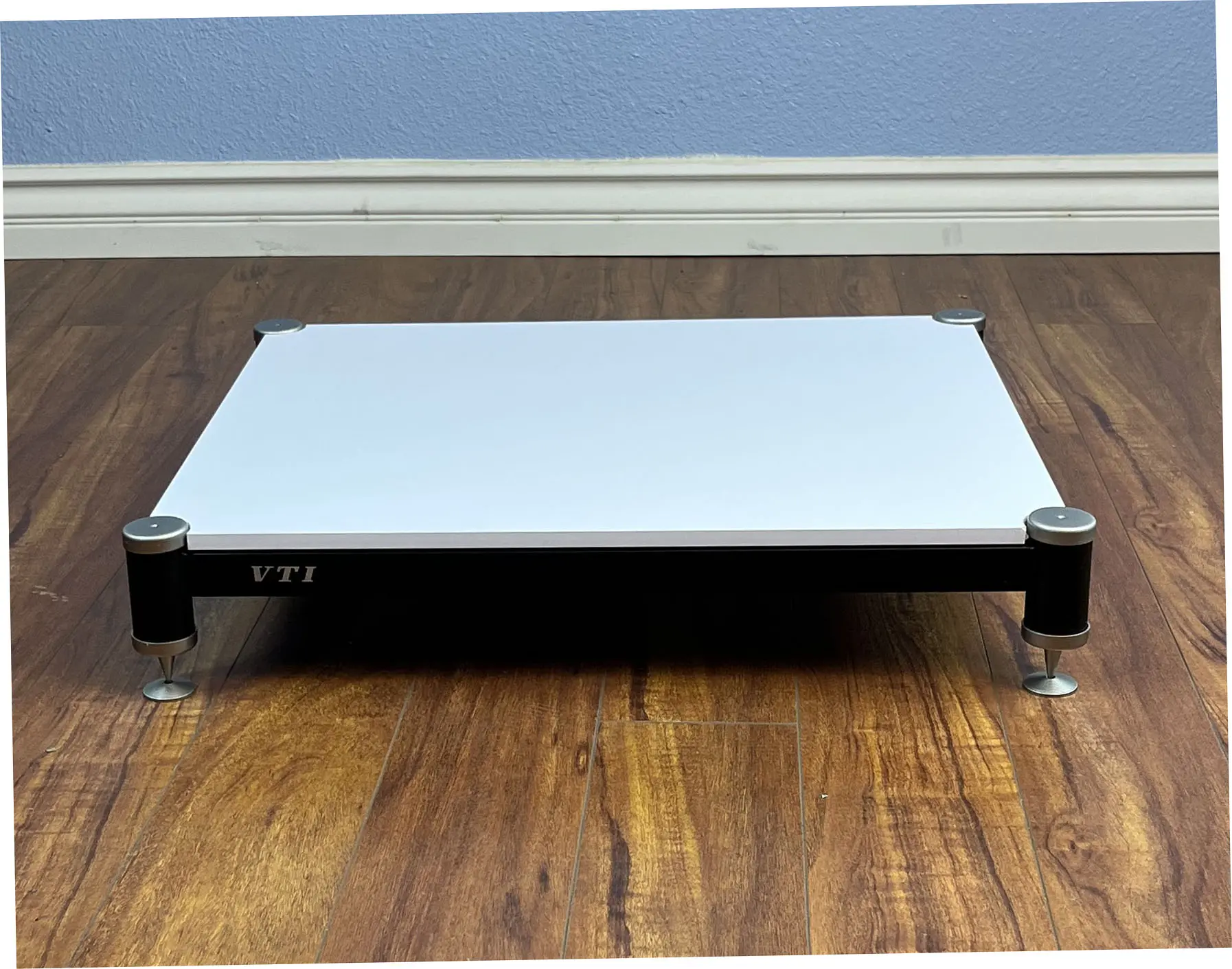 Minimalist white and black laptop stand on wooden floor.