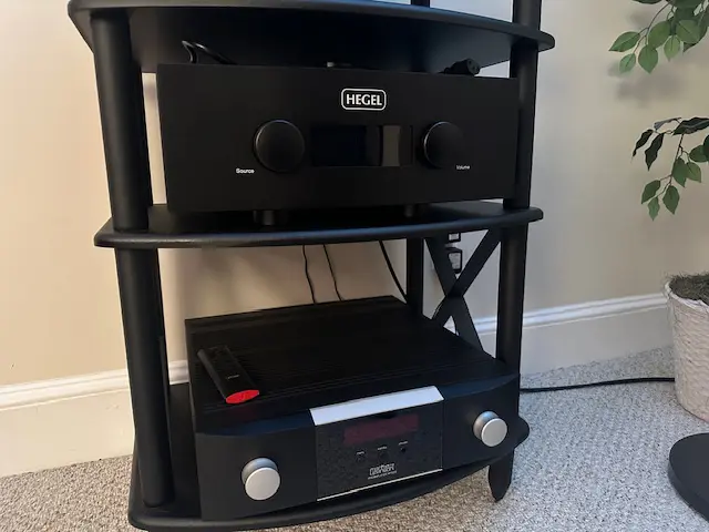 A black audio amplifier and CD player on a black metal rack.