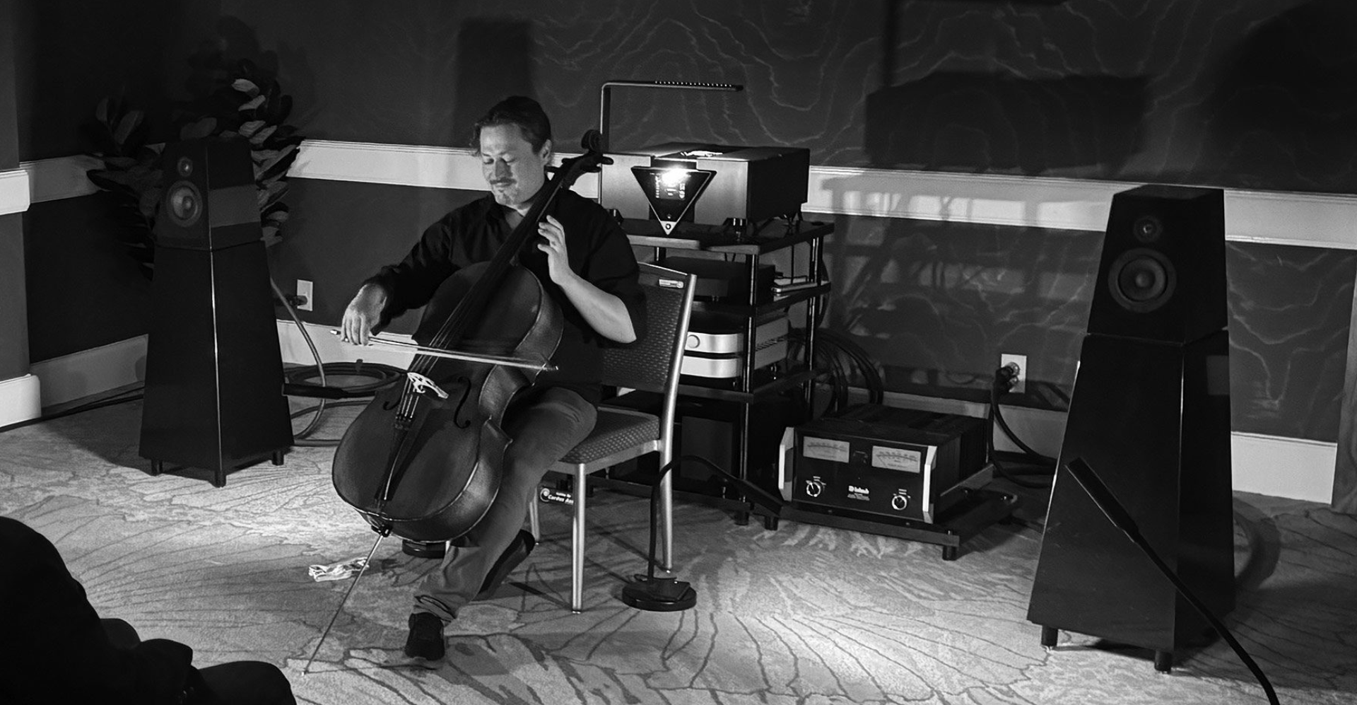 A musician playing cello in a dimly lit room.