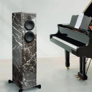 A sleek marble speaker beside a grand piano in a modern room.
