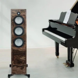 A grand piano next to a tall speaker with multiple drivers.