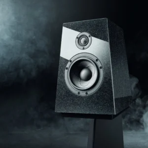 A modern black speaker emitting smoke in a dark setting.