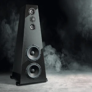 A sleek black speaker with multiple drivers standing on a smoky floor.